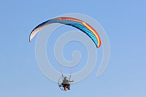 Paramotor pilot flying in a blue sky