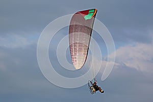 Paramotor pilot flying in a cloudy sky