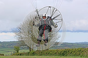 Paramotor pilot landing in a field