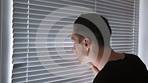 Paranoid man, spy, journalist or detective, watches through the blinds