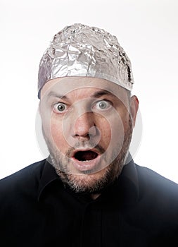 Paranoid man wearing tin foil hat in shock