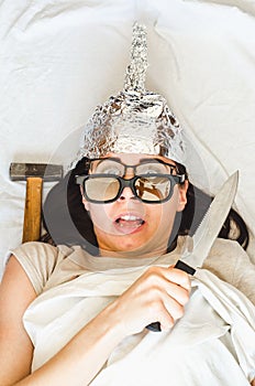 Paranoid woman wears foil hat and tries to protect herself with knife because of mental disease