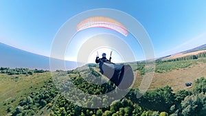 Paraplane flight of a person above the green trees