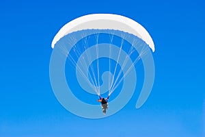 A paraplane flying high up in the deep blue sky