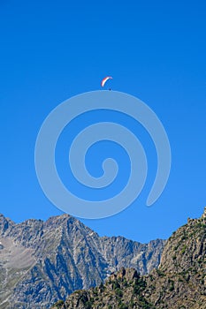 Paraplaners in tandem gliding in blue sky and Alpine mountains on paraplane