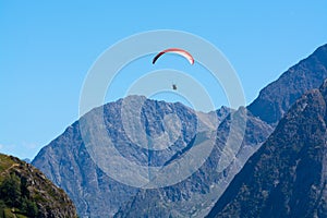 Paraplaners in tandem gliding in blue sky and Alpine mountains on paraplane