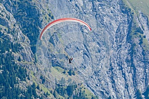 Paraplaners in tandem gliding in blue sky and Alpine mountains on paraplane