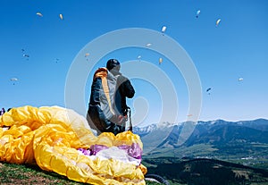 Paraplanner in full equipment for flight looks on soaring another paraplanes in sky