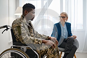 Paraplegic soldier in wheelchair talking with therapist