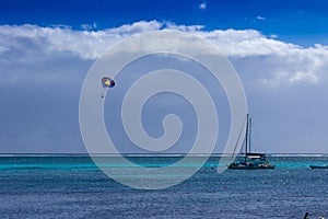 A parasail floats over the blue and azure waters of the Caribbean Sea off of the coast of Belize.
