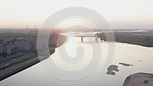 Parasail wing flying on golden sunset horizon landscape. Paraplane flying over river on city bridge architecture background