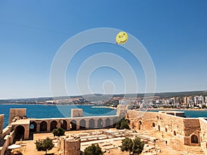 Parasailers above Maiden`s castle or Kizkalesi or Deniz kalesi and view of sea and Kizkalesi town
