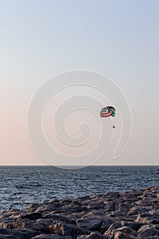 Parasailing in Dubai - single colorful parasail parachute tendem wing flying, towed behind a boat before sunset