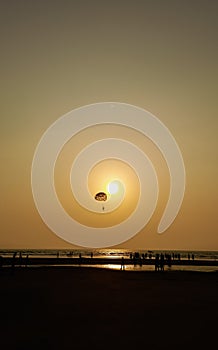 Parasailing extreme sports on beach in sunset background.