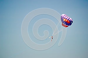 Parasailing. Man flies on parachute in clear blue sky. Side view. Copy space.