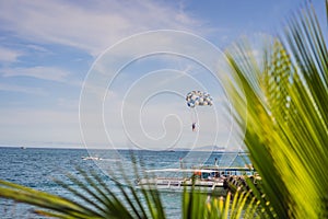 Parasailing water amusement. Flying on a parachute behind a boat on a summer holiday by the sea in the resort. Beautiful