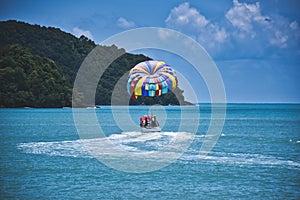 Parasailing on the waves of the azure Andaman sea under the blue sky near the shores of the sandy beautiful exotic and stunning