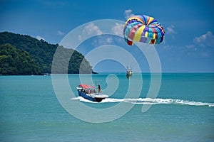 Parasailing on the waves of the azure Andaman sea under the blue sky near the shores of the sandy beautiful exotic and stunning