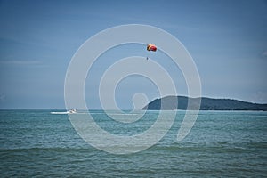 Parasailing on the waves of the azure Andaman sea under the blue sky near the shores of the sandy beautiful exotic and stunning