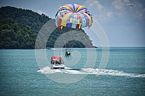 Parasailing on the waves of the azure Andaman sea under the blue sky near the shores of the sandy beautiful exotic and stunning