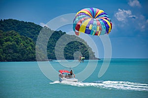 Parasailing on the waves of the azure Andaman sea under the blue sky near the shores of the sandy beautiful exotic and stunning