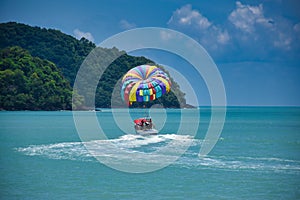 Parasailing on the waves of the azure Andaman sea under the blue sky near the shores of the sandy beautiful exotic and stunning