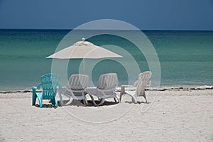 Parasol and sunbeds on empty beach in Progreso by blue ocean in the Caribbean. Vacation in Yucatan, Mexico.
