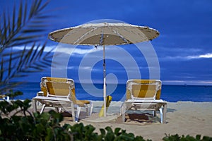 A parasol and two beach beds