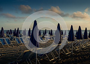 Parasols aligned at Tuscany beach at sunset