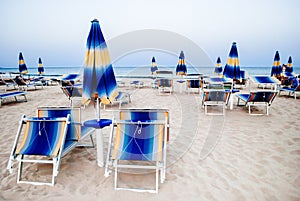 Parasols and deck chairs closed on the beach in the early summer morning