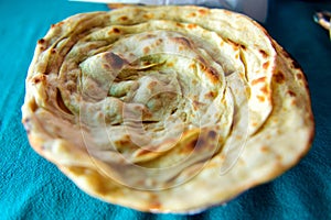 Paratha, round flaky Indian bread from whole wheat, selective focus, close-up. Laacha paratha in restaurant traditional indian