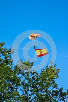 Paratrooper in full flight with the flag of Spain and a helicopter in the background