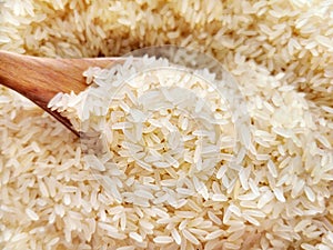 Parboiled rice on wood spoon.  Selective focus.