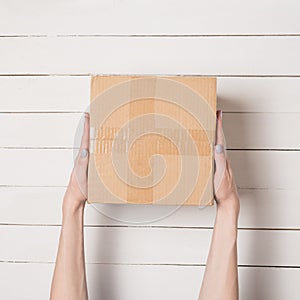 Parcel in female hands. Top view. White table on the background