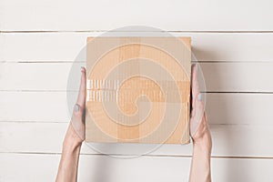 Parcel in female hands. Top view. White table on the background