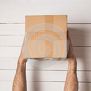 Parcel in male hands. Top view. White table on the background