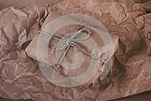 Parcel package wrapped with brown craft paper tied rope. Boxing process. Crumpled paper texture background.