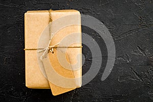 Parcel packaging box wrapped with craft paper with empty label mockup on black background top view copy space