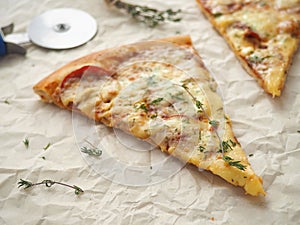 Parchment background with pepperoni pizza. Homemade pizza with thyme.