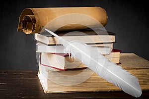 Parchment scrolls and inkwell with a pen on the background of the stack of books