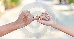 Parent and child hooking their fingers to make a promise