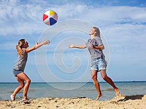 Parent and child play a ball at coast on a summer day