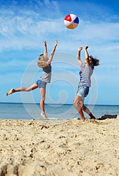 Parent and child play a ball at coast on a summer day