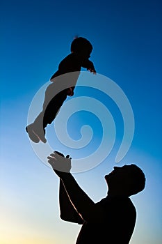 A parent with a child playing on the beach silhouette