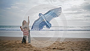 Parent child playing kite on ocean beach weekend. Young single mom helping son