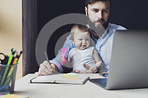 Parent with child studying remotely at homebased laptop. Distant education for people with babies.Man and toddler sitting at table photo