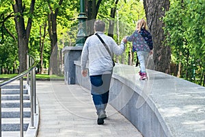 Parent with a child walk in the park rear view. Happy childhood, father and daughter in the park