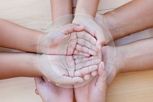 Parent and children holding hands together on wooden background.