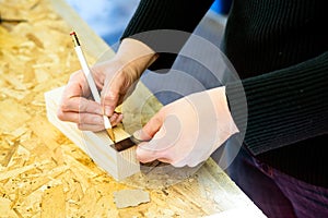 Parent draws stencil on wood block for Pinewood Derby car photo