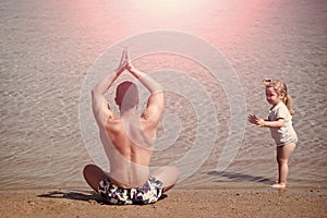 Parent example. yoga for all. father and child doing yoga exercises on beach